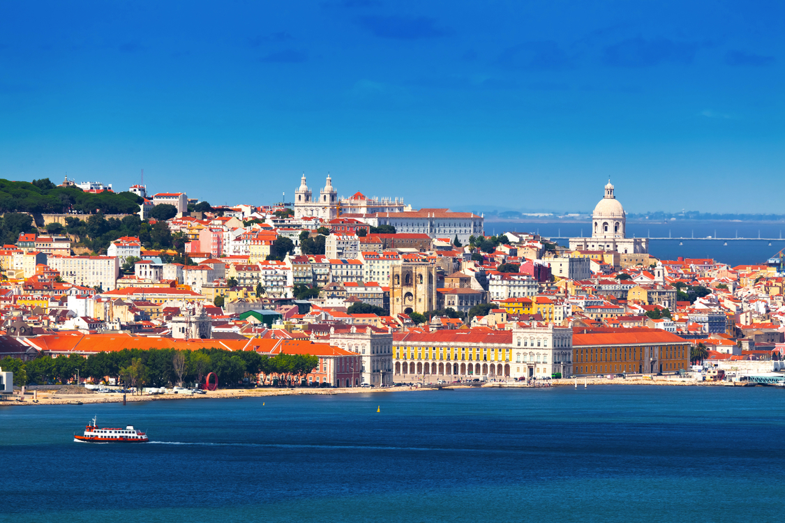 Küstenpanorama von Lissabon mit historischen Gebäuden und einem Fährschiff.
