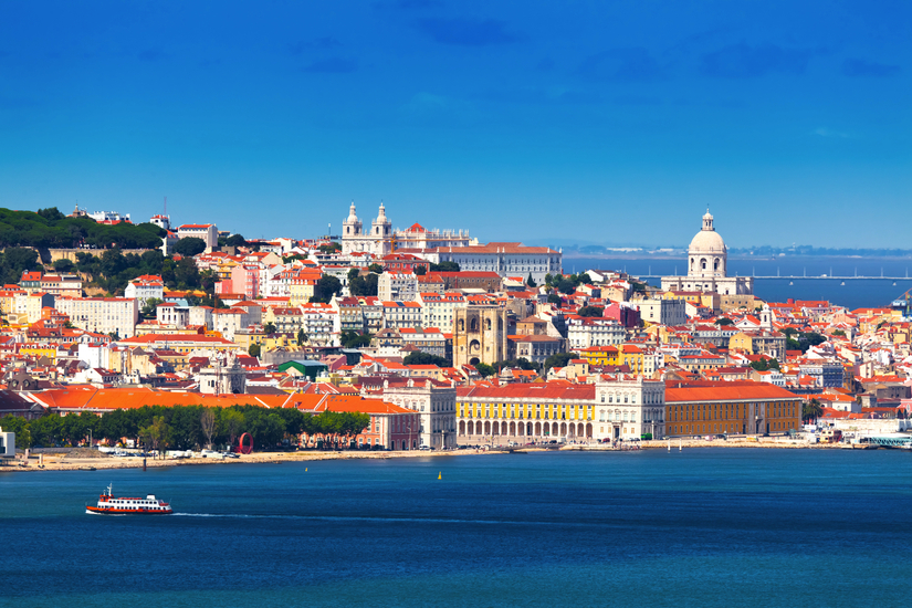 Küstenpanorama von Lissabon mit historischen Gebäuden und einem Fährschiff.