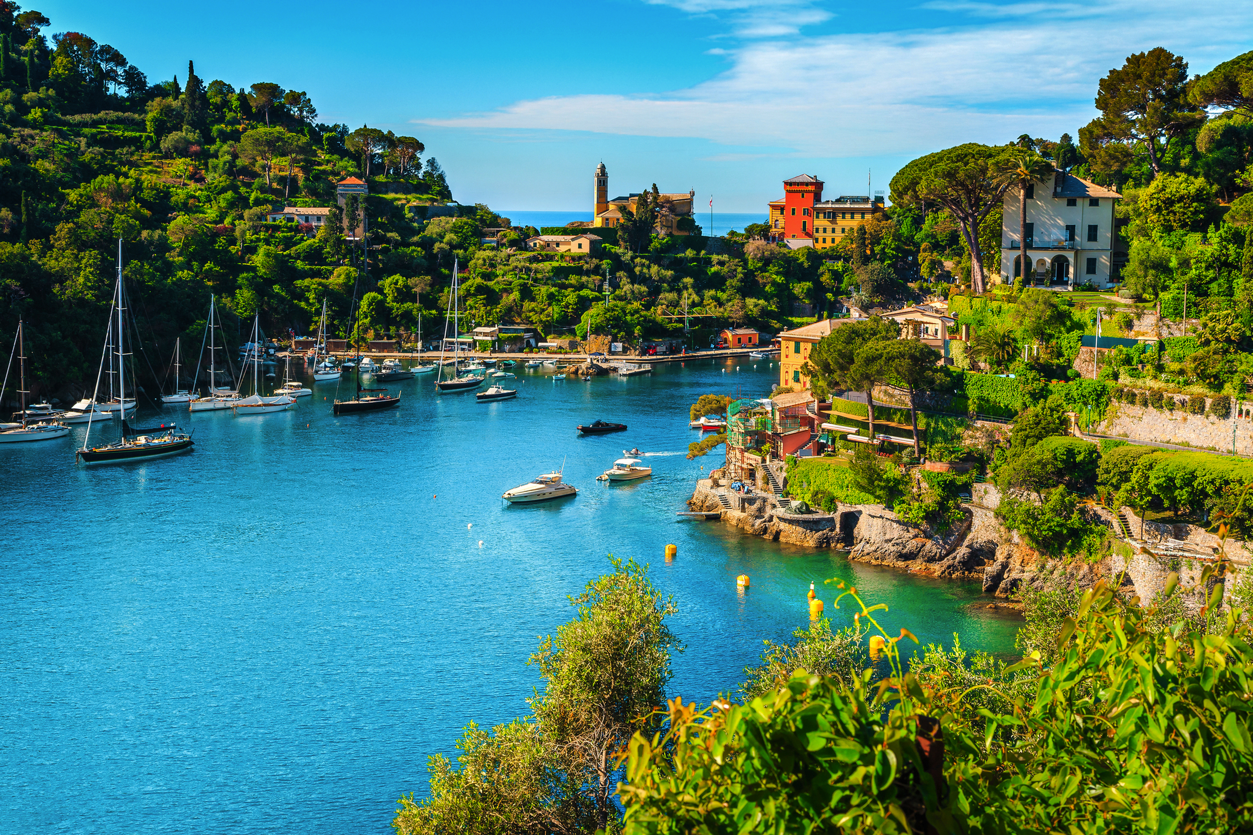 Blick auf eine malerische Bucht mit Booten und grünen Hügeln im Hintergrund.