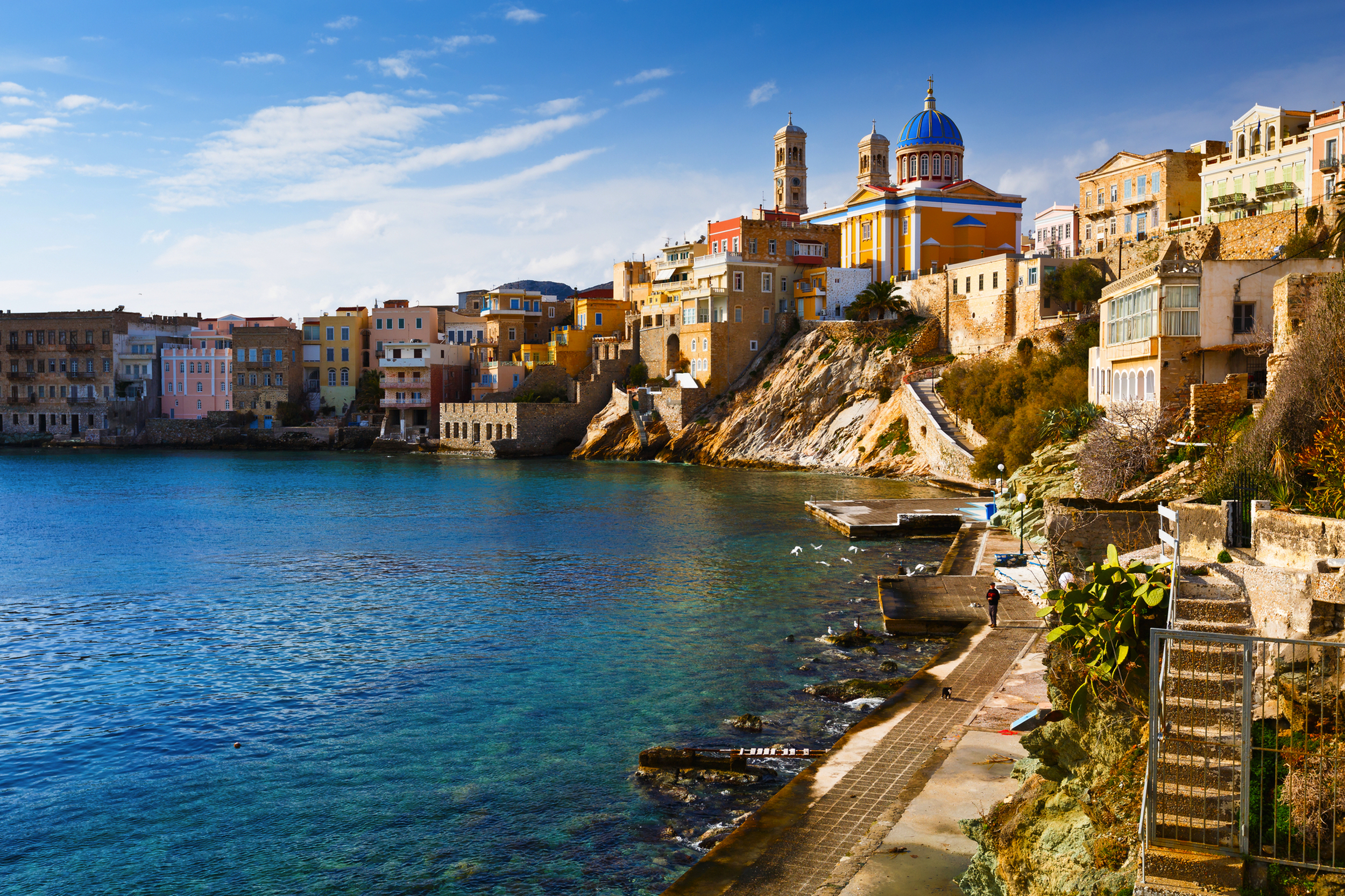 Küstenstadt mit bunten Häusern und Kirche am Wasser.