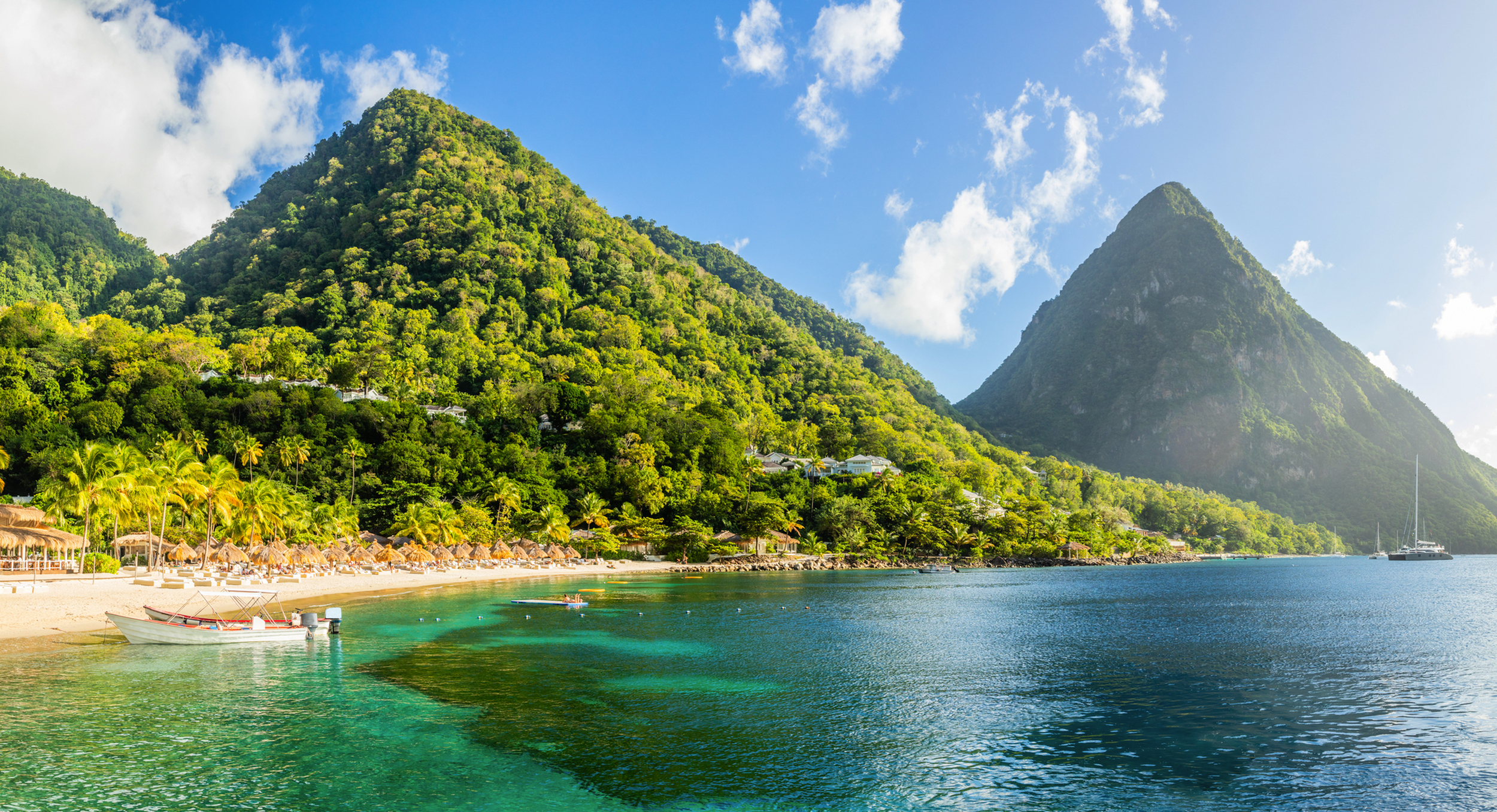 Strand und Meer vor tropischen Bergen unter blauem Himmel
